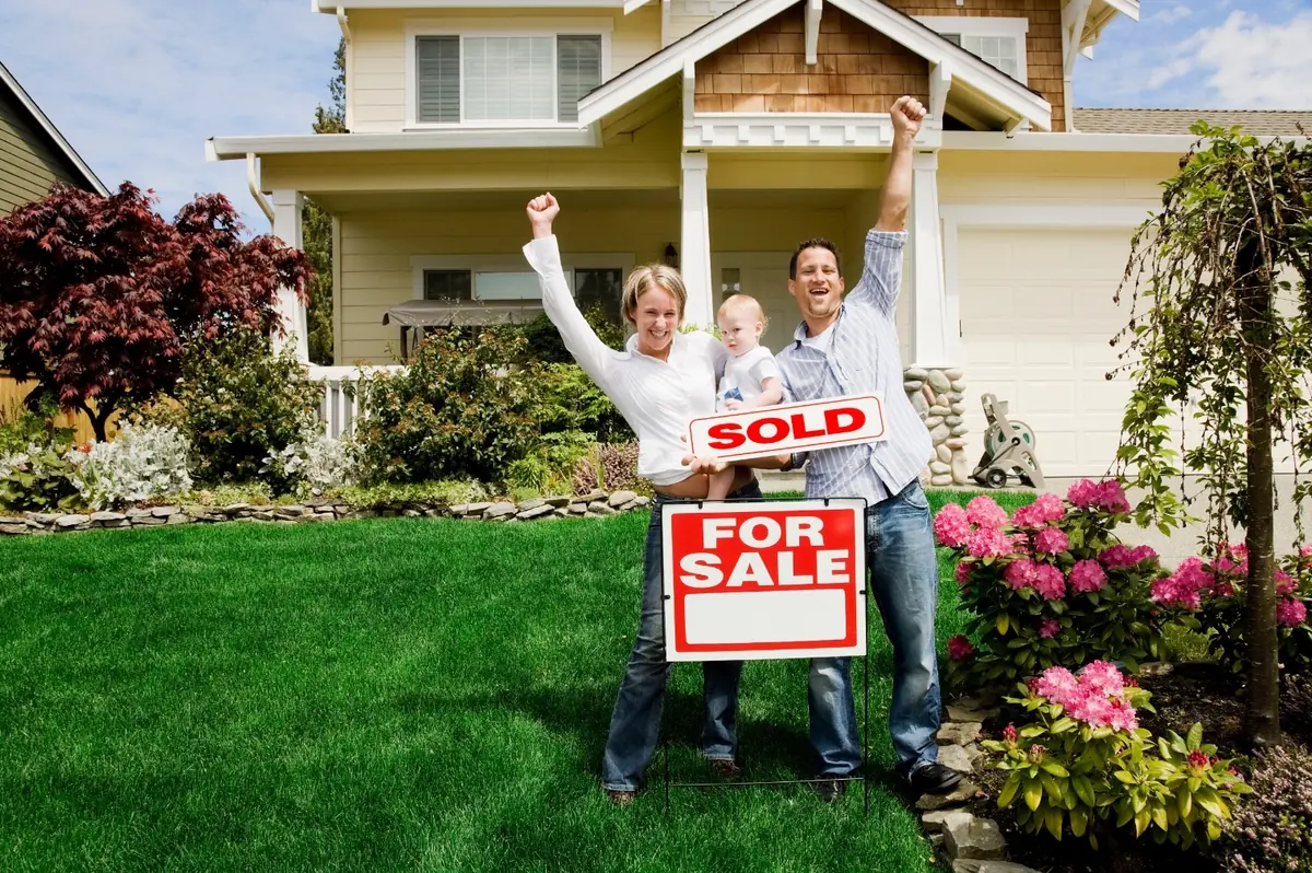 A family holding a SOLD sign in front of the Texas home they sold with ListingSpark